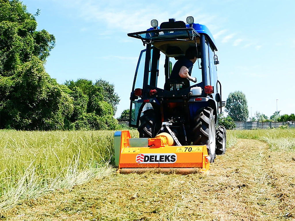Compact tractor with DELEKS APE flail mower cutting tall grass and brush