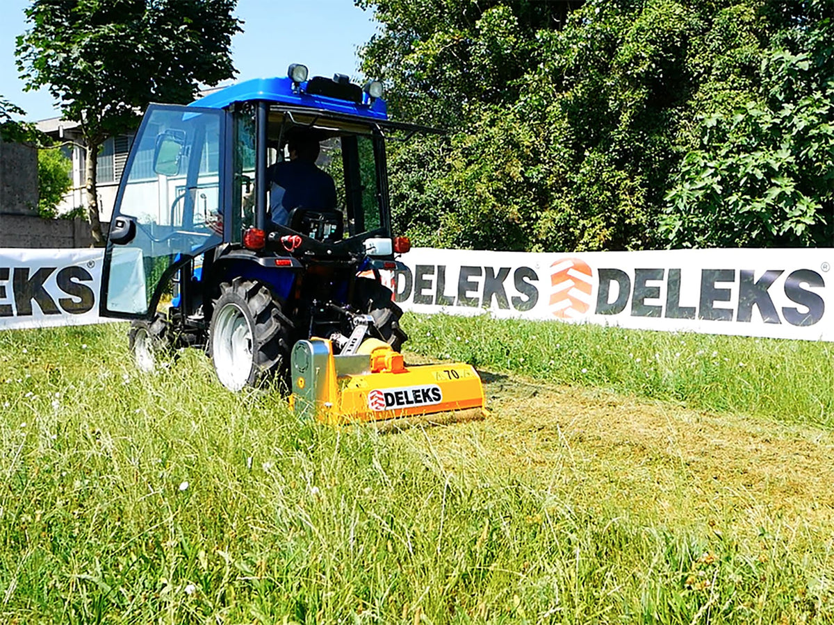 DELEKS APE flail mower mounted on a compact tractor mowing tall grass