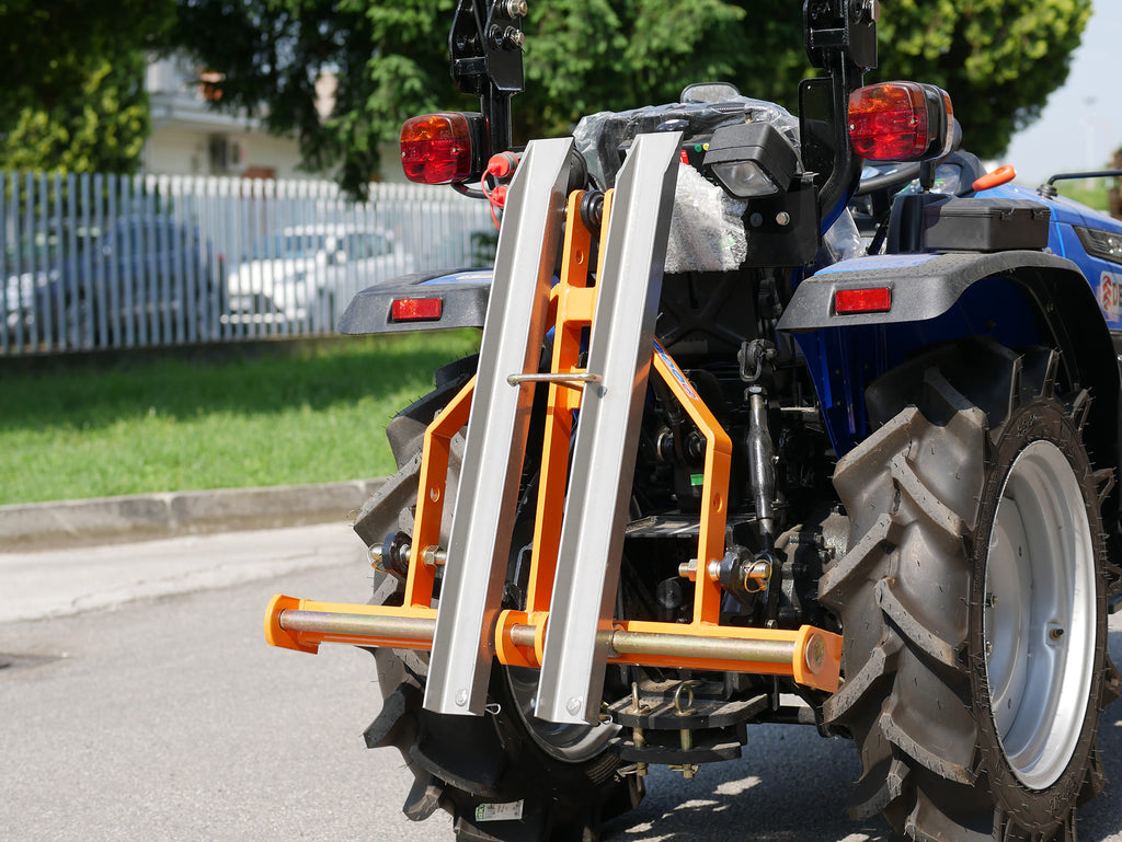 Compact tractor with DELEKS D-300 pallet forks raised, side view