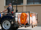 Compact tractor moving a crate with DELEKS D-300 pallet forks