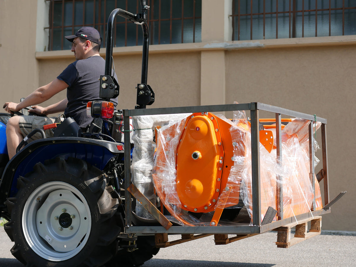 Compact tractor moving a crate with DELEKS D-300 pallet forks