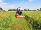 Tractor cutting tall grass in a field with the DELEKS GIRAFFA flail mower