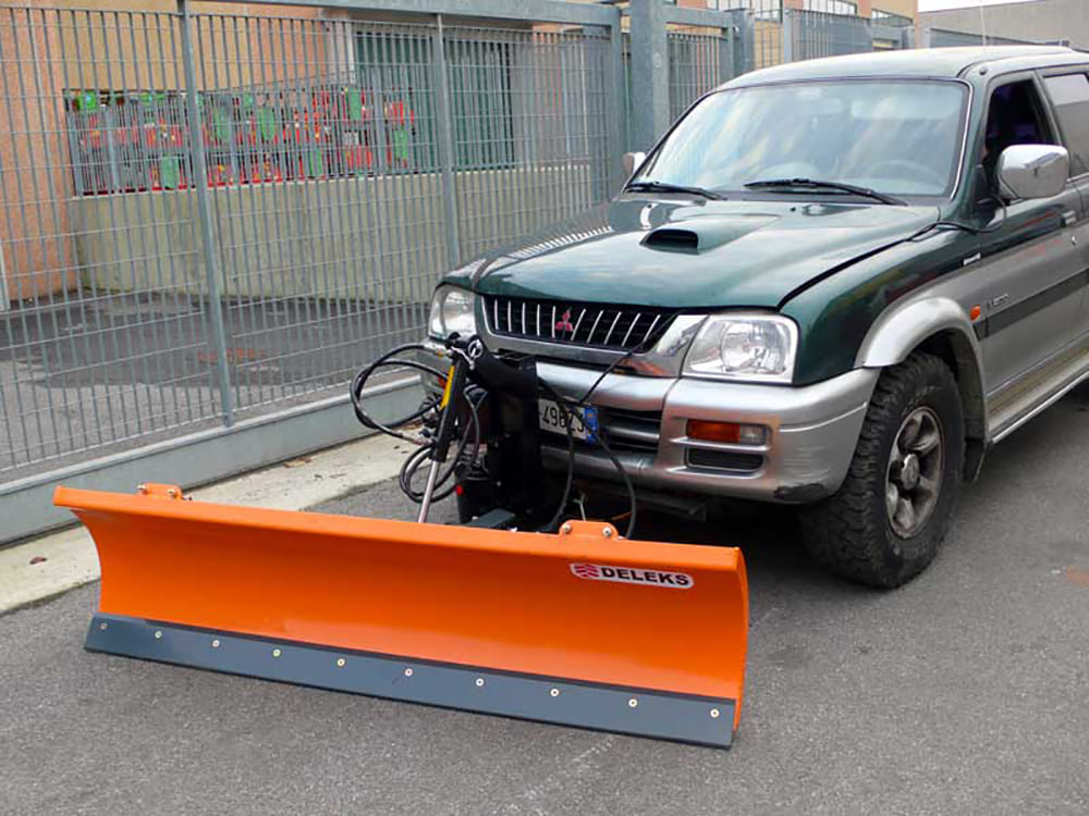 DELEKS LNS-J snow plow mounted on a 4x4 pickup, front three-quarter view